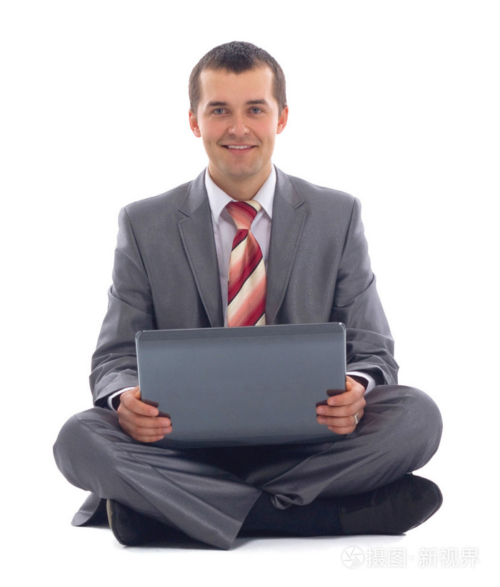 便携式计算机上工作的快乐的年轻商业男子