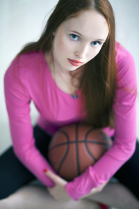 美丽的长发女孩拿着一个篮子球和坐
