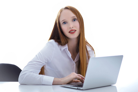 在桌上使用一台便携式计算机的年轻商业女人