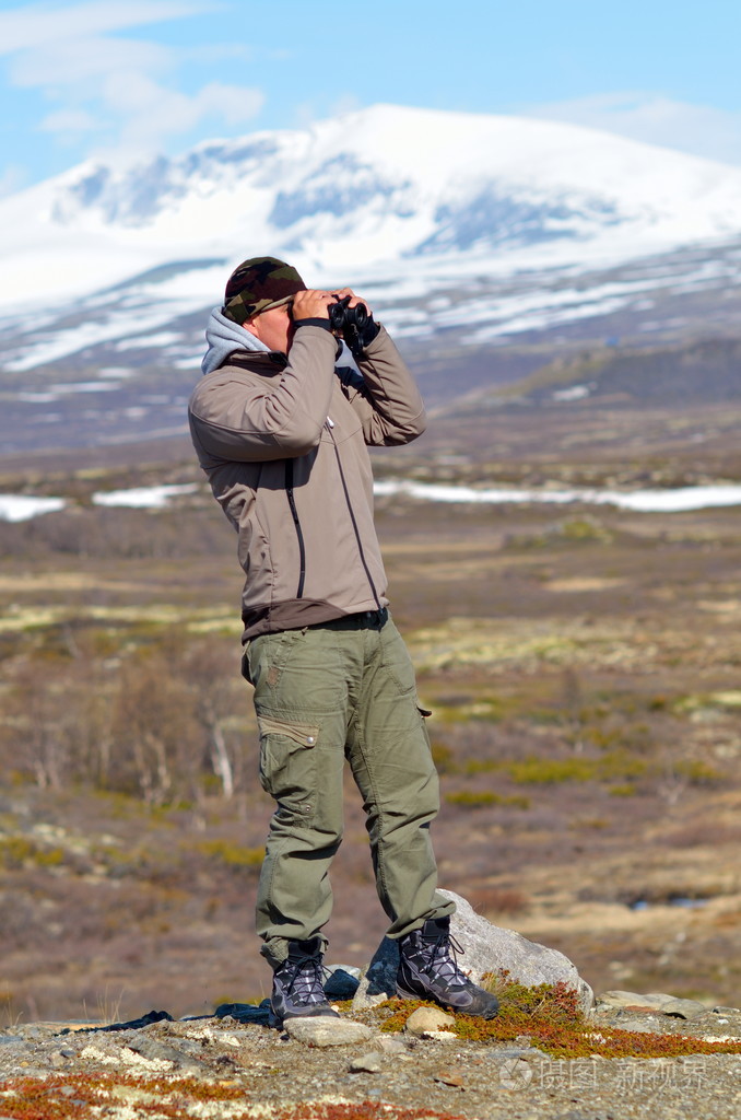 使用双筒望远镜户外的年轻人