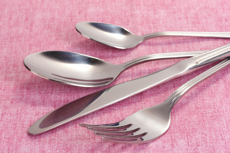 叉子 勺子和粉色桌布上刀