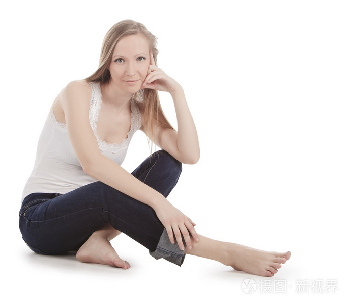 美丽的年轻女子坐在白色的地板上赤脚