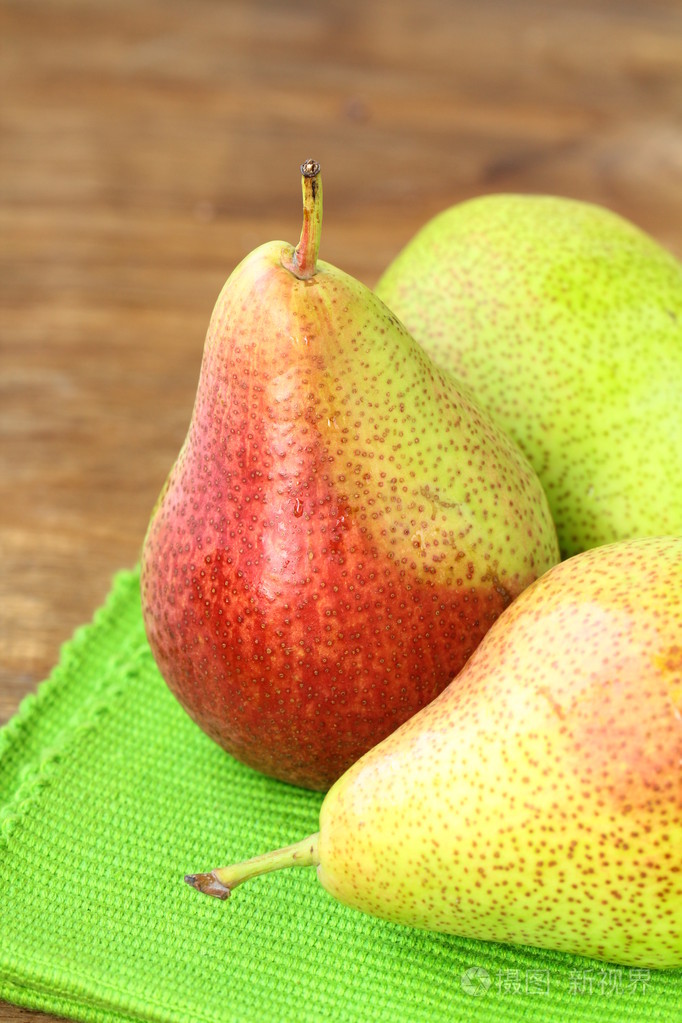 木桌上的三个成熟多汁梨