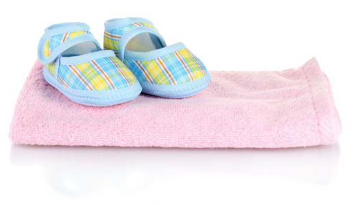 孤立在白色的粉红色毛巾上的蓝色婴儿鞋