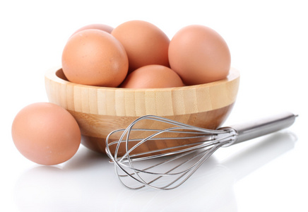 金属扫为搅打鸡蛋和棕色鸡蛋在孤立在白色的木碗