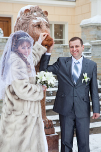 美丽新新婚俄罗斯夫妇拍照与狮子雕塑在冬季