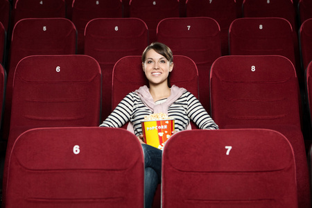 在电影院的爆米花的年轻女人图片