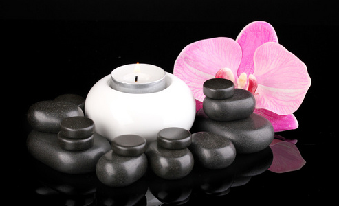 水疗中心的石头与兰花花和孤立在黑色的蜡烛