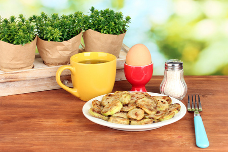 炒的西葫芦鸡蛋和咖啡的绿色背景上的木桌上的早餐