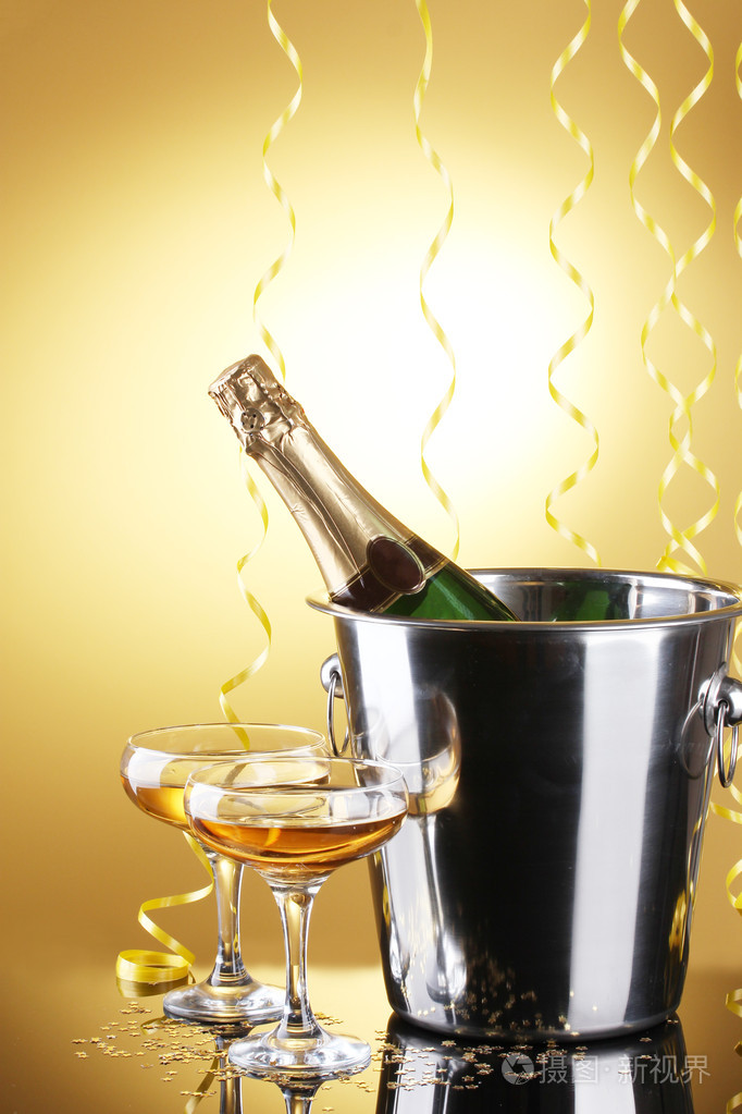 与冰和眼镜的香槟，在黄色背景上的存储桶中的香槟瓶