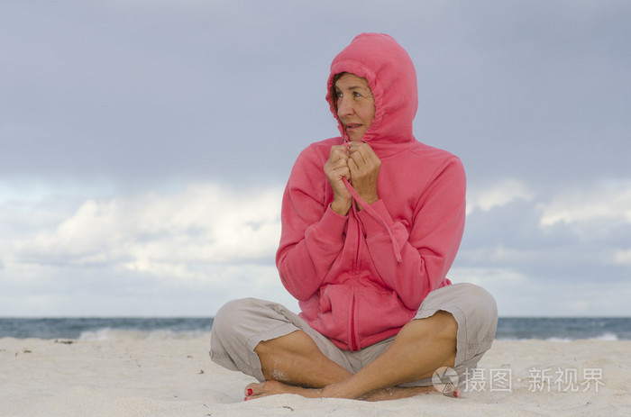 成熟的女人美丽微笑风大冷的天在海滩上