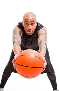 篮球运动员站和持有球上白色隔离室画像。他手臂上的纹身