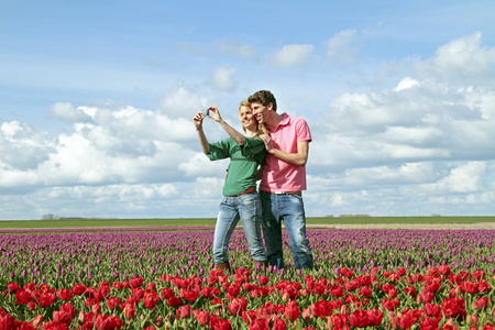 年轻快乐夫妇在郁金香的字段的一张图片
