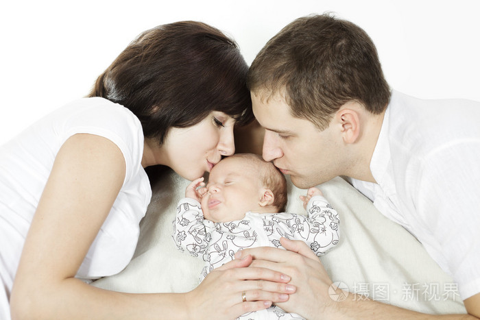 接吻初生婴儿的父母。家庭之爱