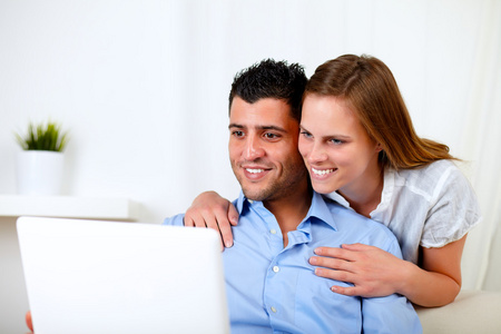 微笑着的年轻夫妇使用的便携式计算机