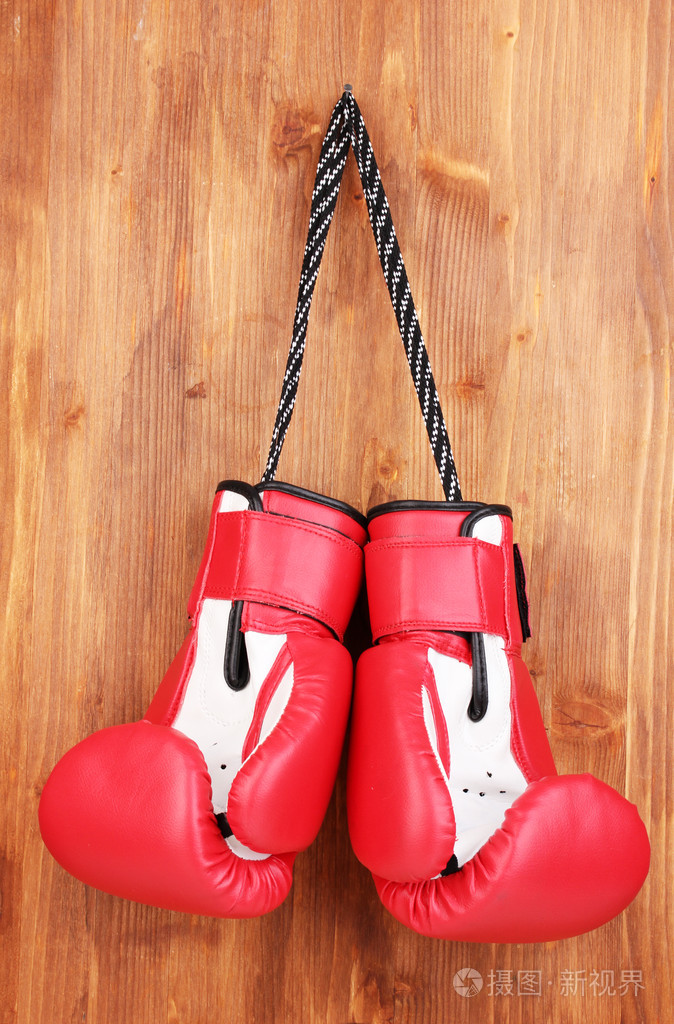 木制背景上挂着的红色拳击手套