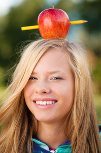 年轻的学生女孩与她的头上的苹果