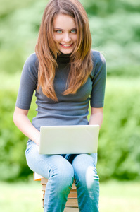 快乐的学生女孩在便携式计算机上工作