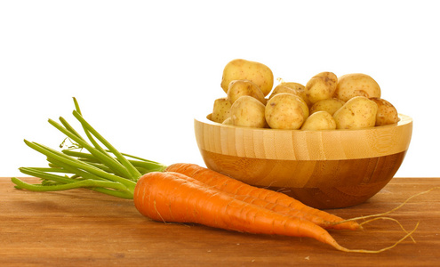 年轻土豆在一个木碗用红萝卜在白色背景上的表