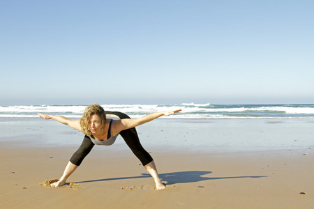 年轻健康的女性做瑜伽练习的海滩