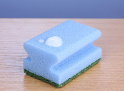 用洗洁精在蓝色背景上的木桌上海绵