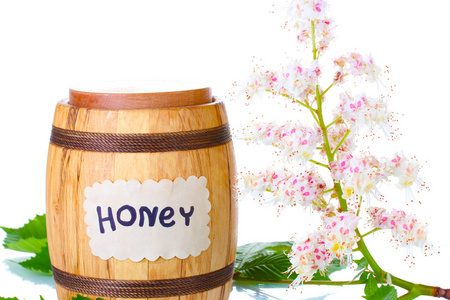 一桶上白色背景特写的蜂蜜和栗子花