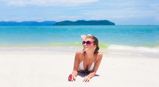 美丽的年轻女子穿着比基尼躺在热带海滩上