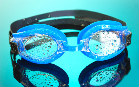 与滴在蓝色背景上的蓝色泳镜