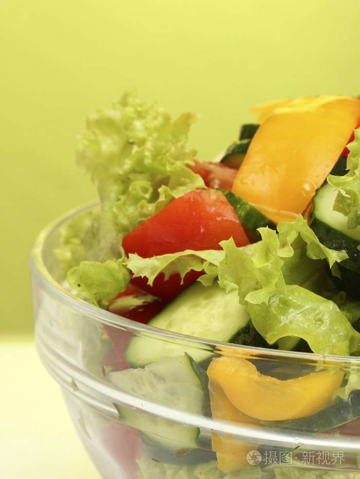 在绿色背景上的透明碗新鲜蔬菜沙拉