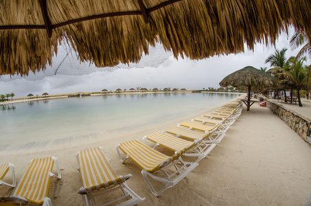 秸秆的伞和椅子上的罗阿坦岛，洪都拉斯海滩