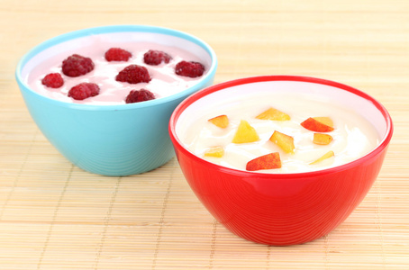 与桃子和树莓在竹垫上碗酸奶图片