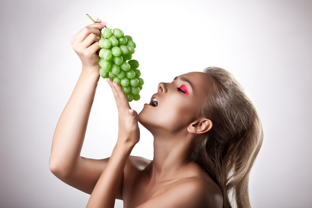 漂亮的年轻女人吃绿色葡萄