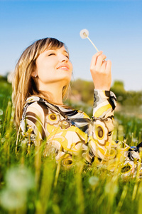 有吸引力的年轻女孩，在一片草地上放松 持有蒲公英花