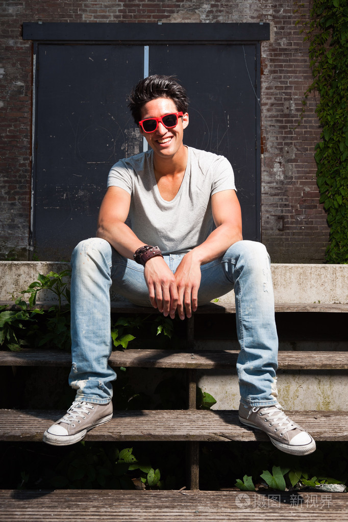 酷的家伙.身穿灰色衫和牛仔裤.老被忽视大厦在背景中