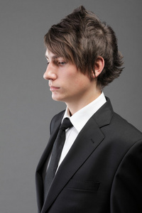 年轻的商人黑色西装休闲领带灰色背景