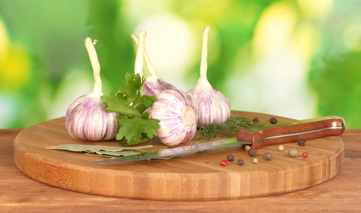 年轻大蒜对绿化 胡椒与绿色背景上的木桌上的刀切板
