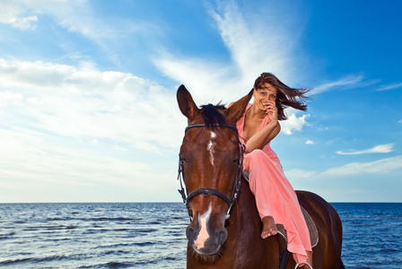 马在海岸上的漂亮女孩