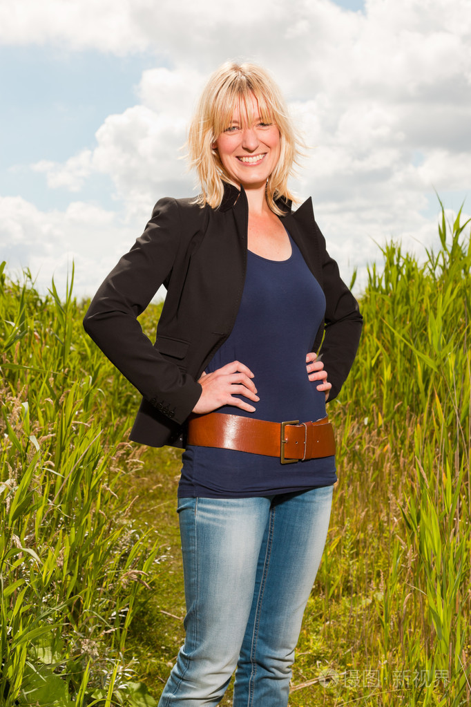 享受自然的快乐年轻漂亮金发女郎.具有高草的字段.蓝多云的天空.