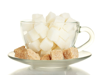 白色的精制的糖和块状棕色甘蔗糖多维数据集在玻璃杯子上白色隔离