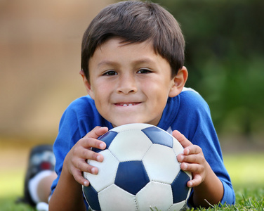 年轻的西班牙裔男孩躺着足球球