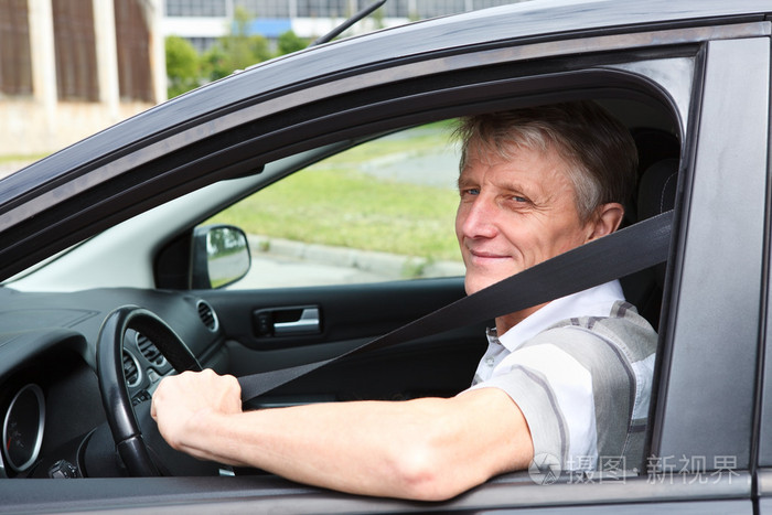 快乐的白种人高级人紧固坐在车上驾驶员座位安全带