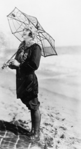 一把伞，看起来像一张蜘蛛网与海滩上的年轻女子