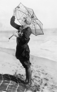 一把伞，看起来像一张蜘蛛网与海滩上的年轻女子