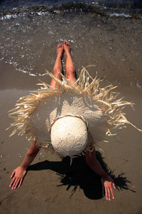 一个戴着帽子的热带海滩上的女孩