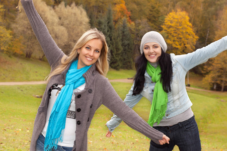 两个快乐年轻妇女在秋天的森林