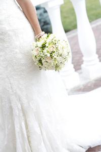 新娘举行白色婚礼花束的玫瑰和爱花