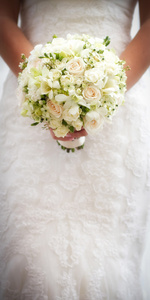 新娘举行白色婚礼花束的玫瑰和爱花