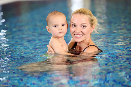 性格开朗的年轻妈妈和小儿子在游泳池