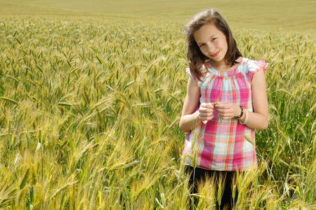 年轻漂亮的女孩在小麦的字段