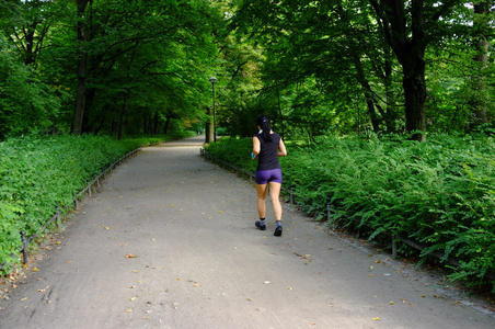 年轻美丽的白种女人在夏天公园慢跑